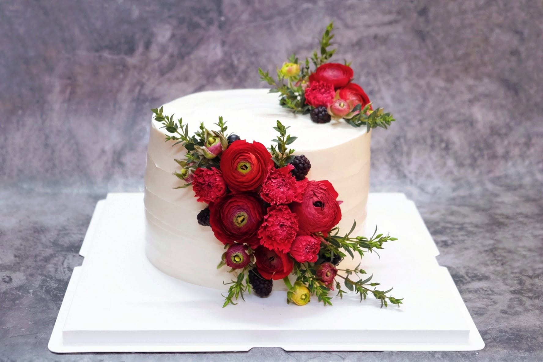 White cake with red ranunculus
