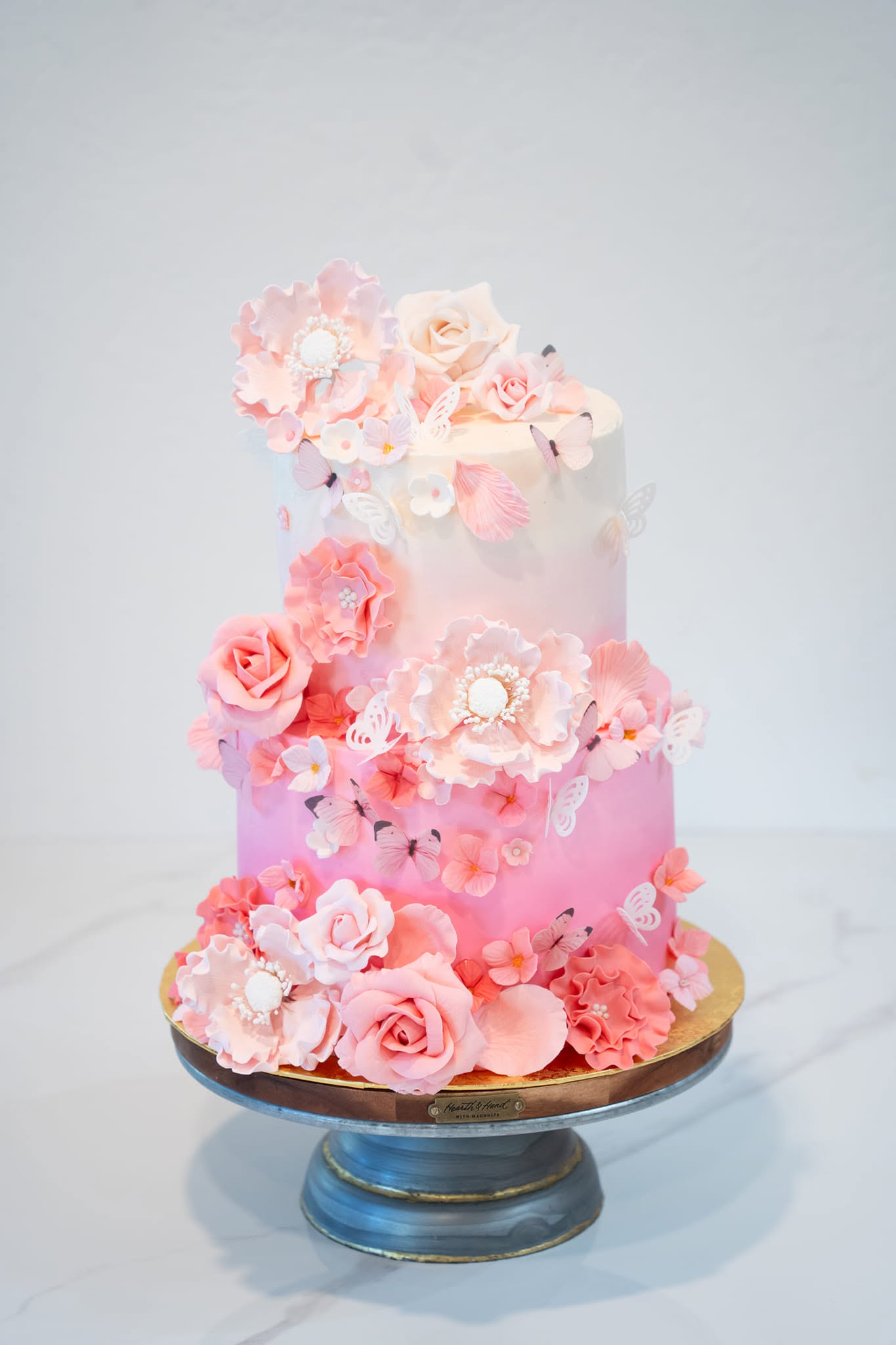 Pink ombré two-tier cake with sugar flowers and butterflies